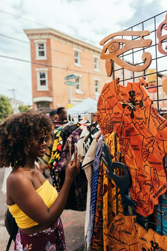 Shopper browsing African-print clothing and handmade crafts at ODUNDE