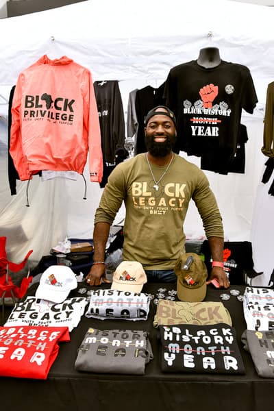 Vendor proudly displaying Black Legacy merchandise and apparel